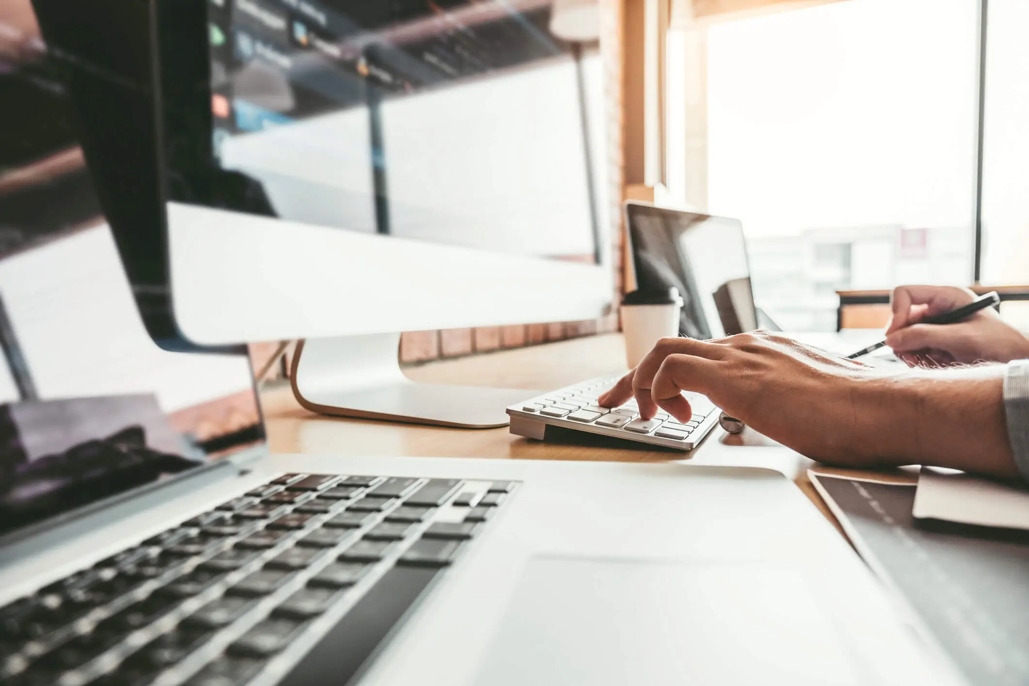 view of mans hands working on multiple computers profusely